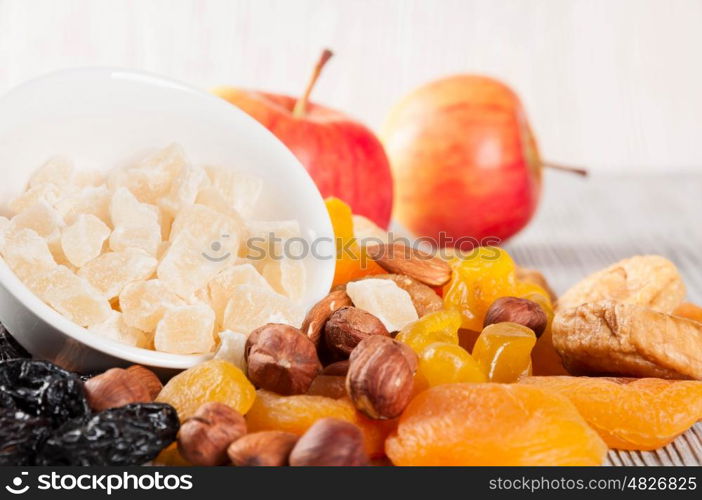 Dried fruits, red ripe apples and nuts on a wooden background