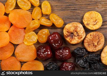 Dried fruits scattered on a wooden background. Top view. Candied fruits, lemon, apricot, fig and dates.