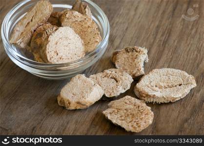 Dried Galangal Slices, In Glass Dish, Up On A Wooden Kitchen Surface
