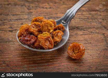 dried goldenberries on a tablespoon against rustic scratched wood