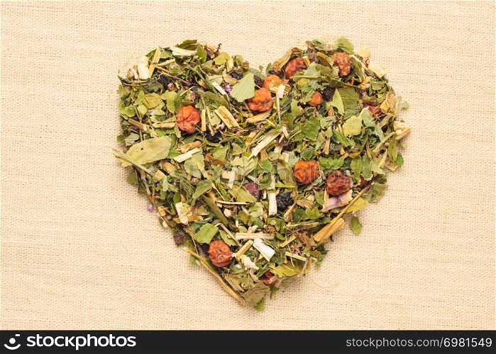 Dried herb leaves heart shaped on burlap jute surface. Herbaceous dry aromatic plant. Healing herbs herbal medicine concept.. Dried herb leaves heart shaped on jute surface