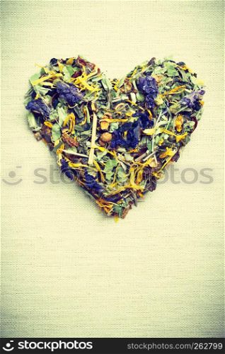 Dried herb leaves heart shaped on burlap surface. Herbaceous dry aromatic plant. Healing herbs herbal medicine concept.. Dried herb leaves heart shaped on burlap surface