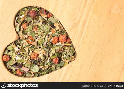 Dried herb leaves heart shaped on wooden surface. Herbaceous dry aromatic plant. Healing herbs herbal medicine concept.. Dried herb leaves heart shaped on wooden surface