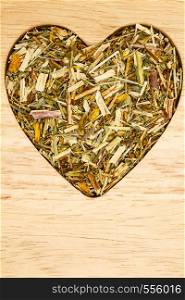 Dried herb leaves heart shaped on wooden surface. Herbaceous dry aromatic plant. Healthy cooking concept.. Dried herb leaves heart shaped on wooden surface