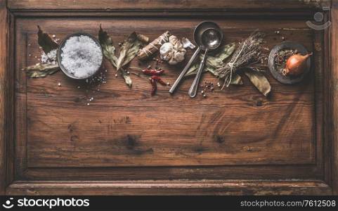 Dried herbs and spices for cooking or canning on rustic wooden background. Top view. Seasoning flat lay. Healthy home cuisine. Food flavoring concept. Border