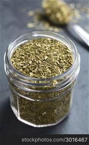 Dried leaves of yerba mate tea, a traditional tea in South-America, photographed in glass jar on slate (Selective Focus, Focus one third into the tea leaves) . Yerba Mate Tea Leaves