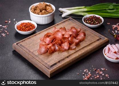 Dried meat slices with spices and herbs. Snacks for beer On a black stone background. Top view. Snacks, jerky for beer on a black stone background