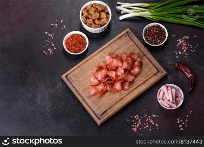 Dried meat slices with spices and herbs. Snacks for beer On a black stone background. Top view. Snacks, jerky for beer on a black stone background
