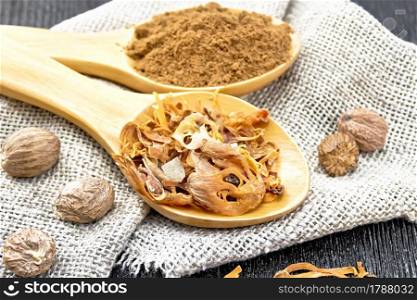 Dried nutmeg arillus and ground nutmeg in two spoons, whole nuts on burlap on a dark wooden board background