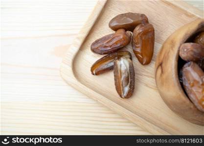 Dried of sweet dates palm fruits on wooden plate. Dates is a dried fruit that provides high energy.