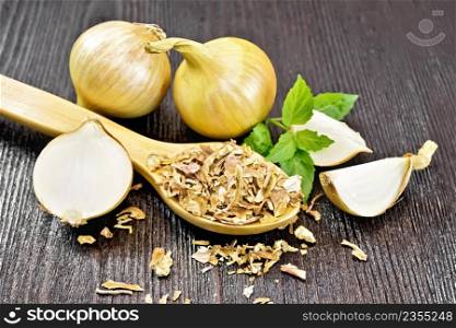 Dried onion flakes in a spoon, yellow onions, basil on dark wooden board background