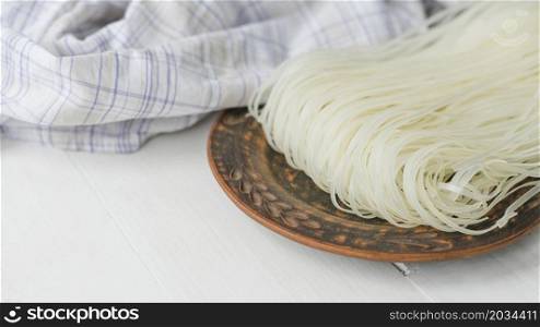 dried rice vermicelli noodles circular plate near checkered cloth white surface