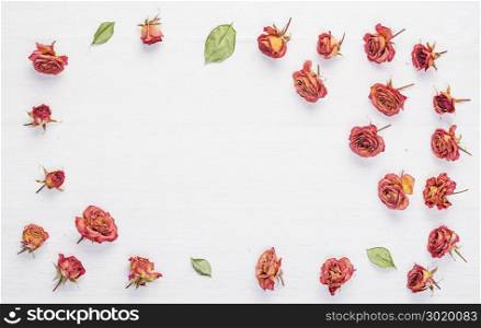 Dried roses flowers on vintage rustic white wooden desk as background.Top view.Concept of love and romantic and passing of time