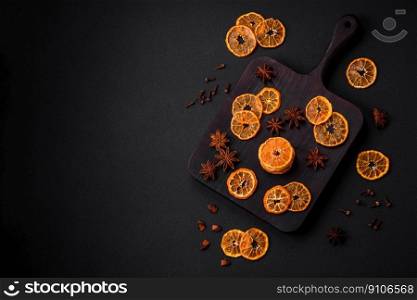Dried round shape slices of bright orange color tangerine on a dark textural background