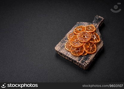 Dried round slices of tangerine, orange or lemon on a dark concrete background. Ingredient for making sweets