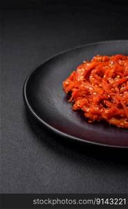 Dried squid chopped into slices and seasoned with sesame seeds and spices on a dark concrete background. Korean cuisine dish