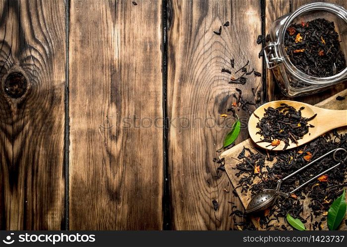 Dried tea jar with a tea spoon and green leaves. On wooden background.. Dried tea jar