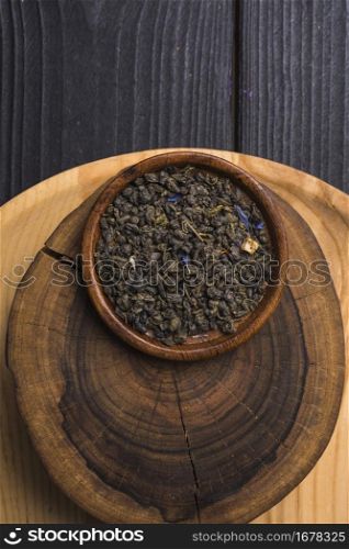 dried tea leaves wooden plate tree stump against table