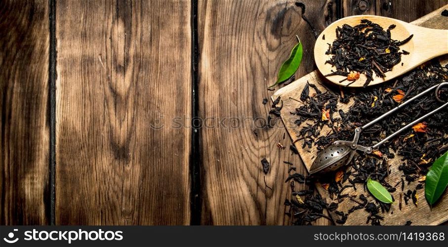 dried tea with spoons. On wooden background.. dried tea with spoons.