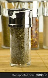 dried thyme in a glass jar on different spices background over wooden mat