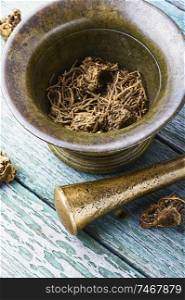 Dried Valerian roots in old bronze mortar.Valeriana officinalis. Valerian herb root