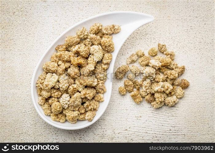 dried white mulberry on a teardrop shaped bowl against rustic barn wood
