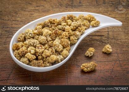 dried white mulberry on a teardrop shaped bowl against rustic wood