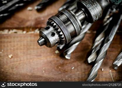 Drill with drills on the table. On a wooden background. High quality photo. Drill with drills on the table.