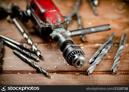 Drill with drills on the table. On a wooden background. High quality photo. Drill with drills on the table.