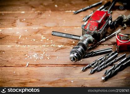 Drill with drills on the table. On a wooden background. High quality photo. Drill with drills on the table.