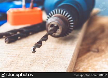 Drills in a power drill on a wooden background. The concept of tools and repair work. Drills for a drill.. Drills in a power drill on a wooden background. The concept of tools and repair work.