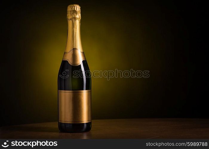 drink, alcohol, advertisement and holidays concept - bottle of champagne with blank golden label on wooden table over dark background