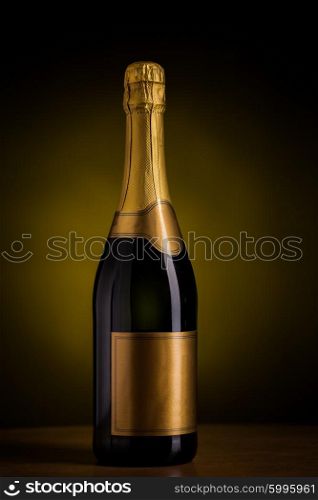 drink, alcohol, advertisement and holidays concept - bottle of champagne with blank golden label on wooden table over dark background