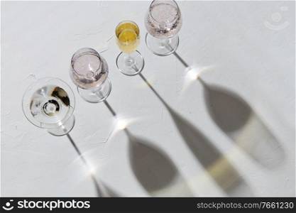 drink, alcohol and glassware concept - different wine glasses dropping shadows on white surface. wine glasses dropping shadows on white surface
