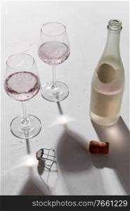 drink, alcohol and glassware concept - wine glasses and open ch&agne bottle dropping shadows on white surface. wine glasses and ch&agne bottle dropping shadows