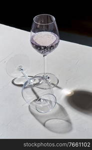 drink, alcohol and glassware concept - wine glasses dropping shadows on white surface. wine glasses dropping shadows on white surface