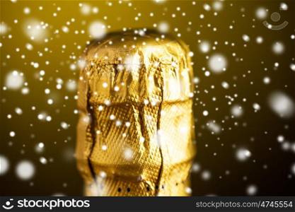 drink, alcohol, christmas, new year and winter holidays concept - close up of champagne bottle cork or top wrapped into golden foil over dark background with snow