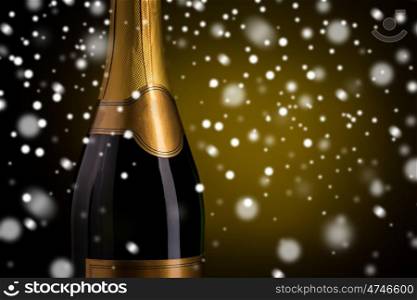 drink, alcohol, christmas, new year and winter holidays concept - close up of bottle of champagne with blank golden label over dark background and snow