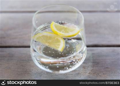 drink and refreshment concept - glass of sparkling water with lemon slices on table. glass of sparkling water with lemon on table