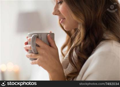 drink, christmas and hygge concept - close up of happy woman with cup of coffee or tea at home. close up of happy woman with cup of coffee at home