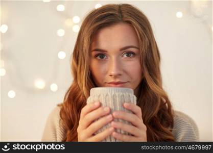 drink, christmas, winter, holidays and people concept - happy young woman with cup of coffee or tea at home