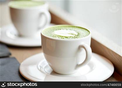 drink, diet, weight-loss and slimming concept - white cup of matcha green tea latte on table at restaurant or cafe