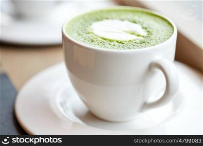 drink, diet, weight-loss and slimming concept - white cup of matcha green tea latte on table at restaurant or cafe