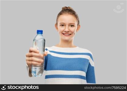 drink, health and people concept - happy smiling teenage girl in pullover with bottle of water over grey background. smiling teenage girl with bottle of water
