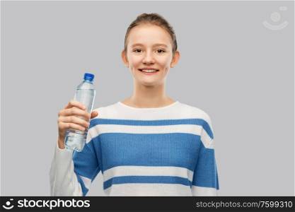 drink, health and people concept - happy smiling teenage girl in pullover with bottle of water over grey background. smiling teenage girl with bottle of water