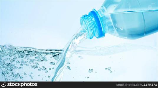 drinking, healthy eating and food storage concept - close up of drinking water pouring from plastic bottle over blue background
