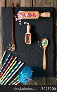 Drinking straws and sugar sprinkle dots on slate background