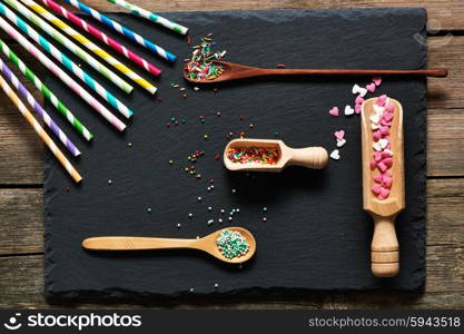 Drinking straws and sugar sprinkle dots on slate background