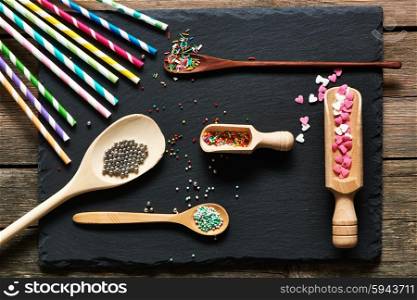 Drinking straws and sugar sprinkle dots on slate background