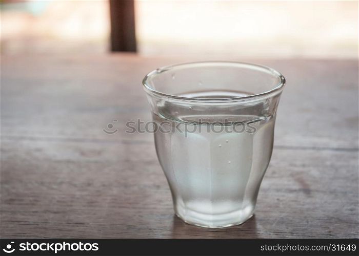 Drinking water in a glass on wooden table, stock photo
